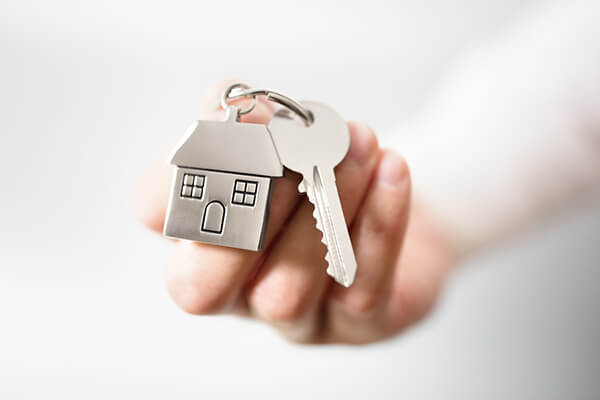 A keychain with a metal house and a key