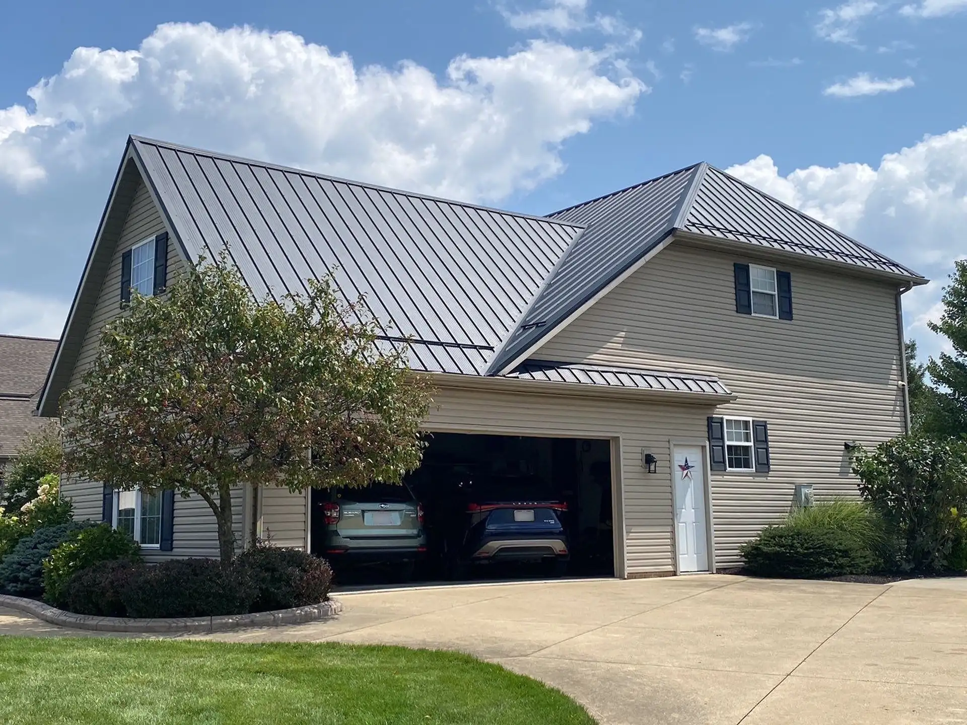Two-story home with standing seam metal roof over attached two-car garage and driveway